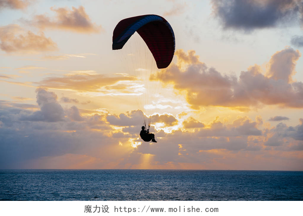 夕阳西下海上的跳伞运动员将军飞越日落海洋的剪影